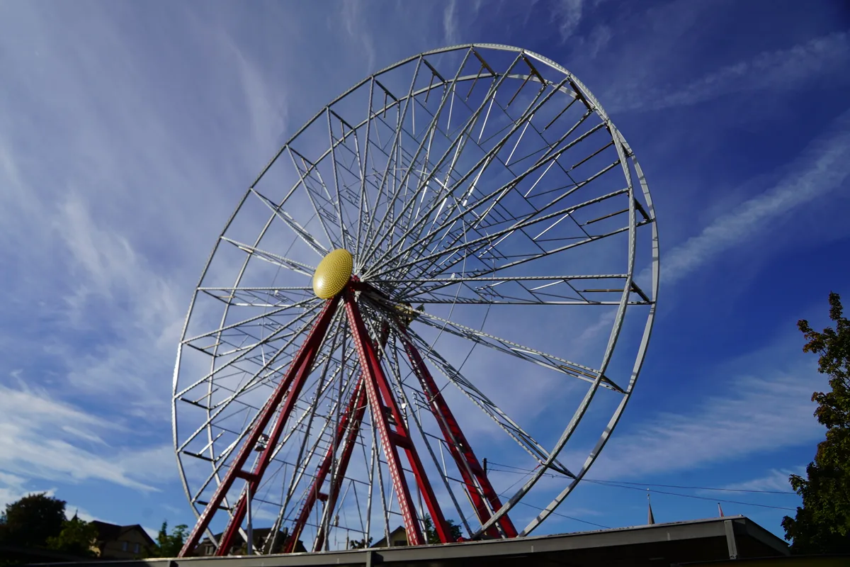 Ein Riesenrad vor strahlend blauem Himmel.